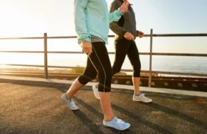 Two individuals running on a path by the ocean, enjoying the view.